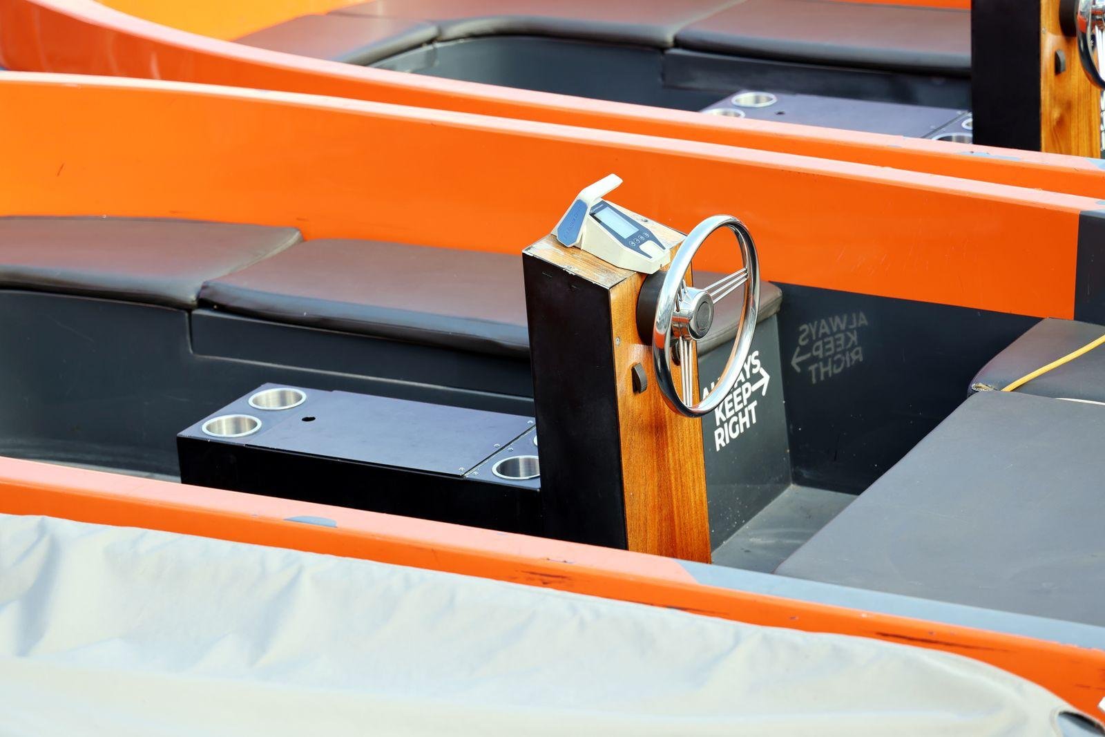 Close-up of cushioned vinyl seating and helm on an orange runabout boat – boat seat upholstery in Auckland