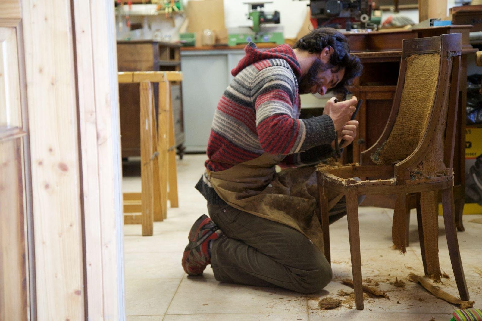 Craftsman repairing the timber frame of a dining chair in a workshop before reupholstery