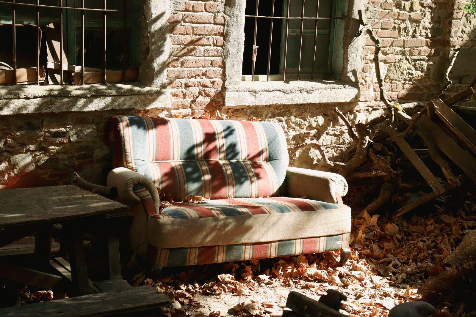 Worn striped sofa with faded fabric but an intact frame – deciding whether an old sofa is worth reupholstering