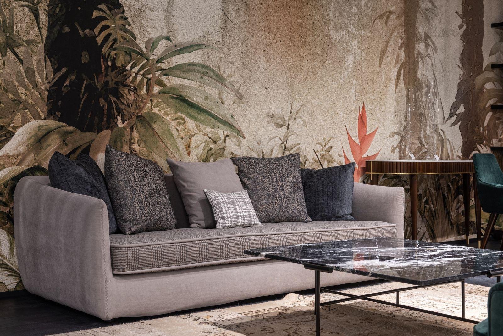 Grey fabric sofa with patterned cushions in front of a botanical feature wall – living room reupholstery ideas for Auckland homes