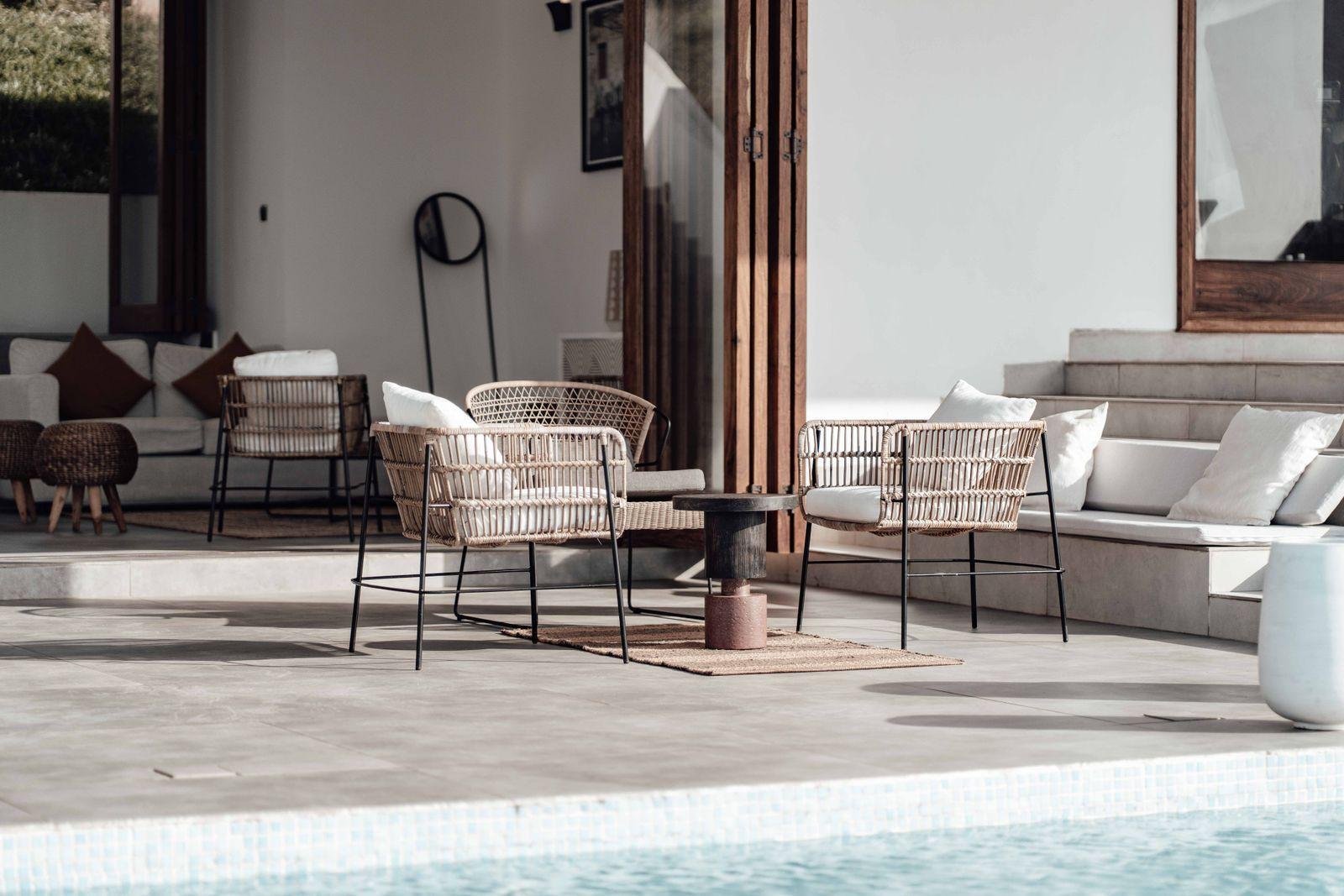 Wicker chairs with white cushions in a covered outdoor living area – indoor-outdoor reupholstery ideas for Auckland homes