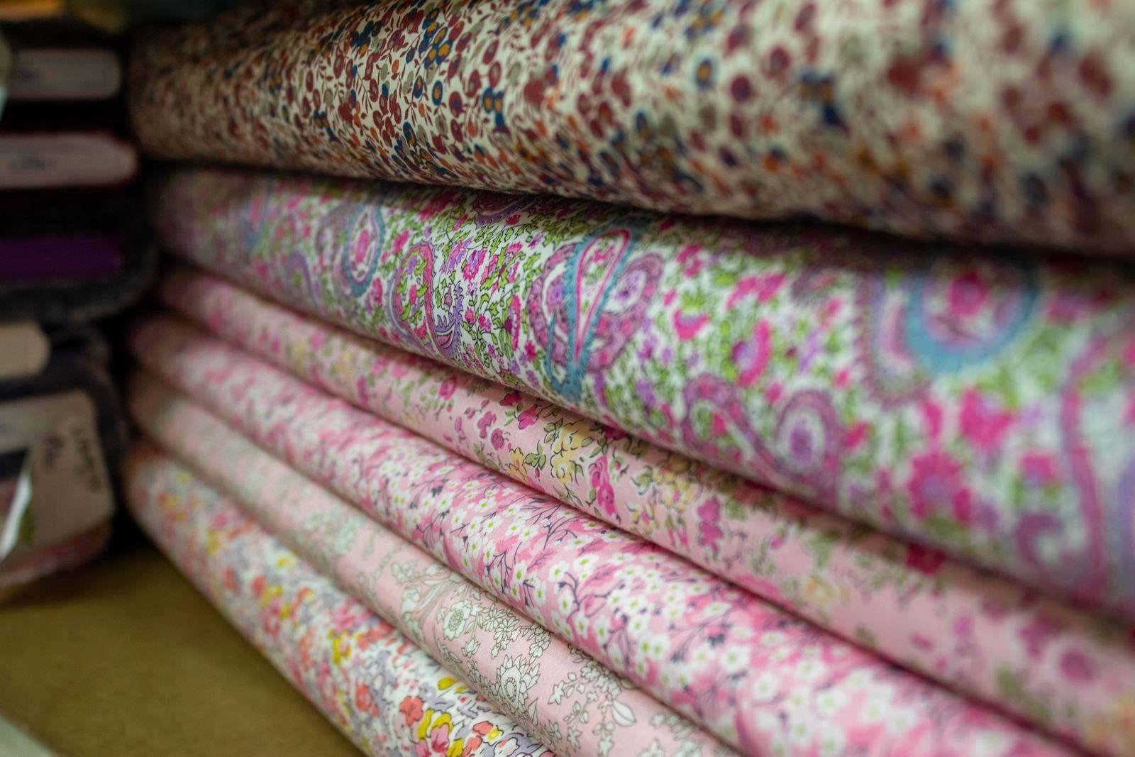 Rolls of patterned upholstery fabric stacked in a fabric store – choosing fabric for reupholstery in East Auckland