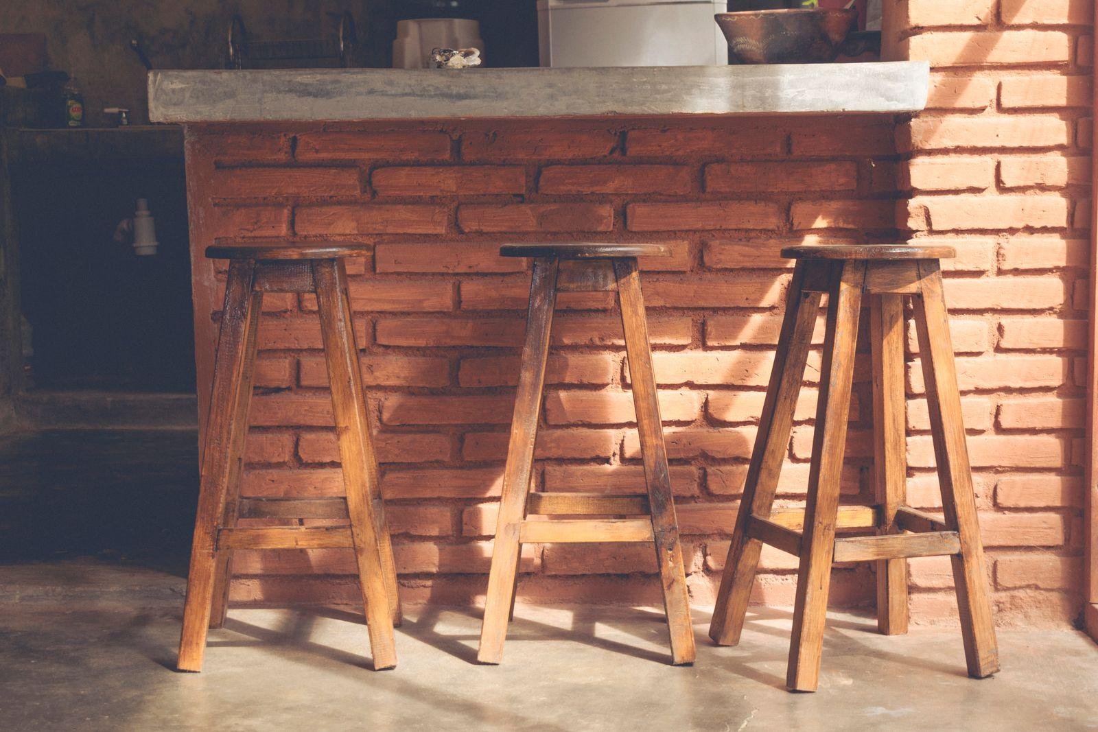 Three timber bar stools at a brick-fronted bar counter – commercial bar stool reupholstery for cafés and venues