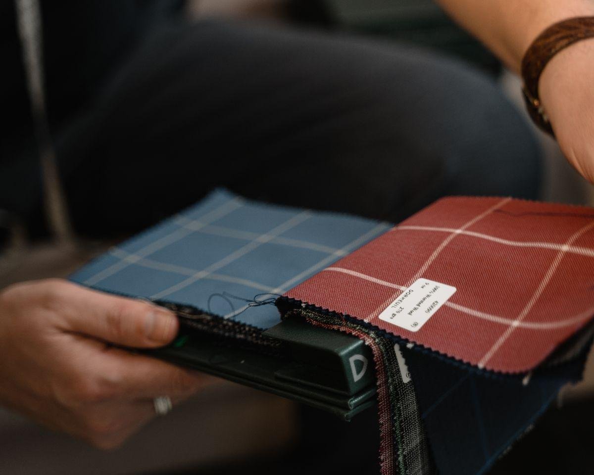Hands holding patterned upholstery fabric swatches for dining chair reupholstery in NZ