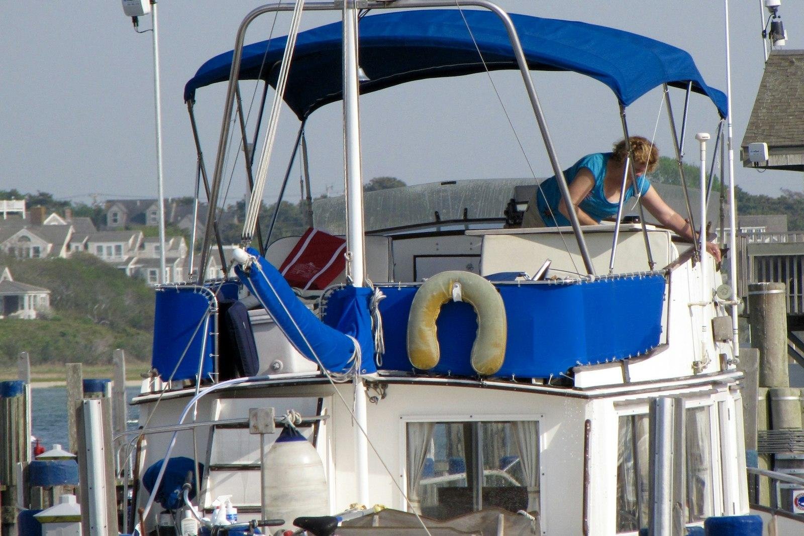 Launch on a marina berth with a blue bimini top and blue canvas side covers