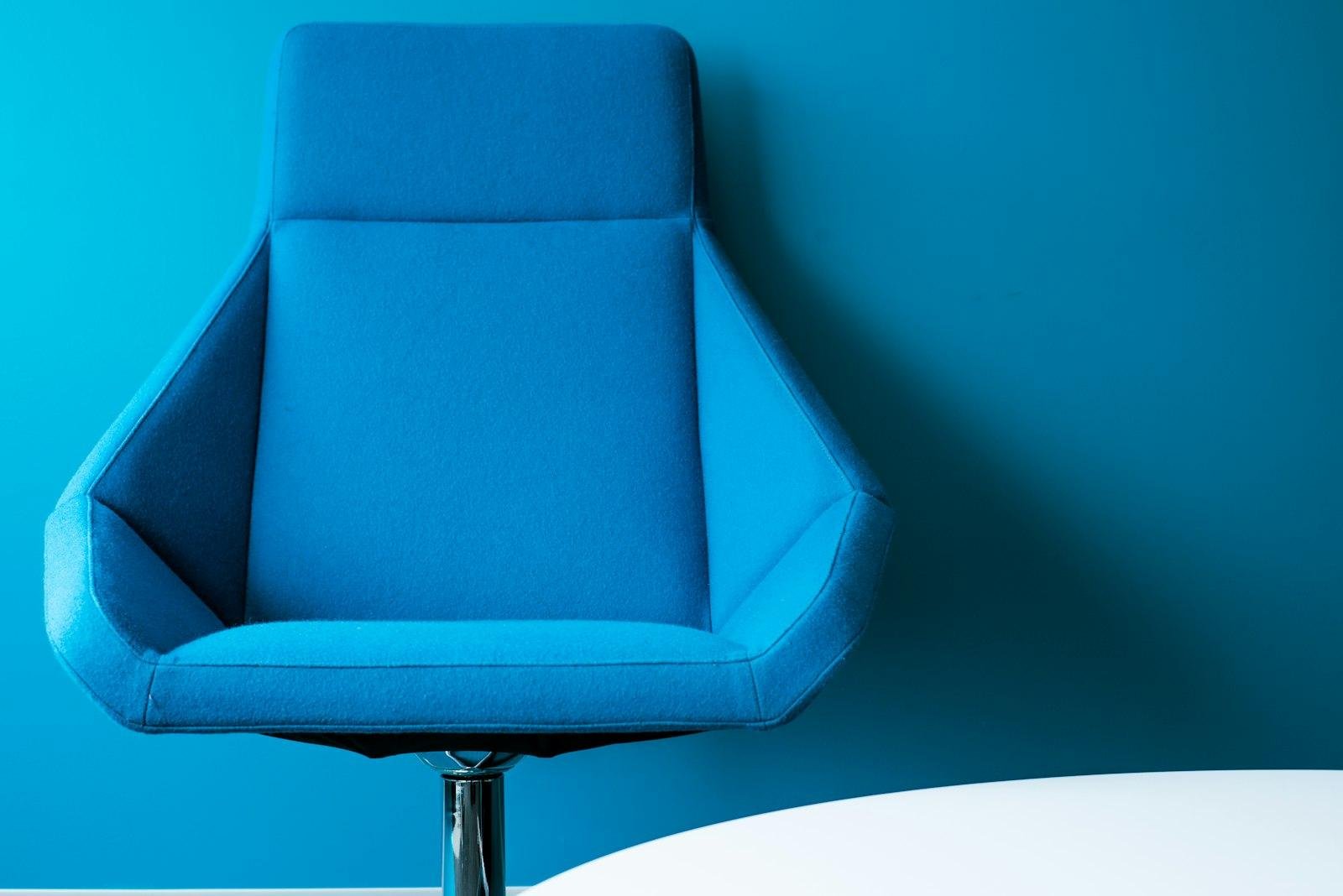 Blue fabric-upholstered swivel office chair against a blue wall