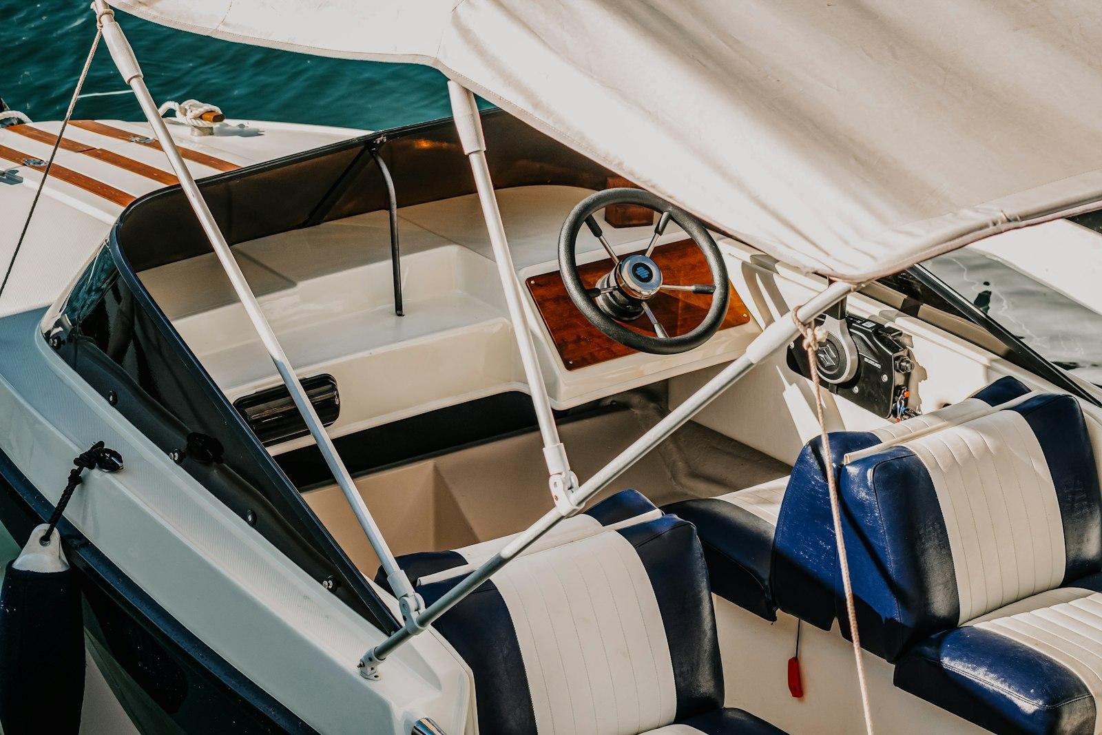 Navy and white vinyl boat seats and helm under a canvas bimini top on a motorboat