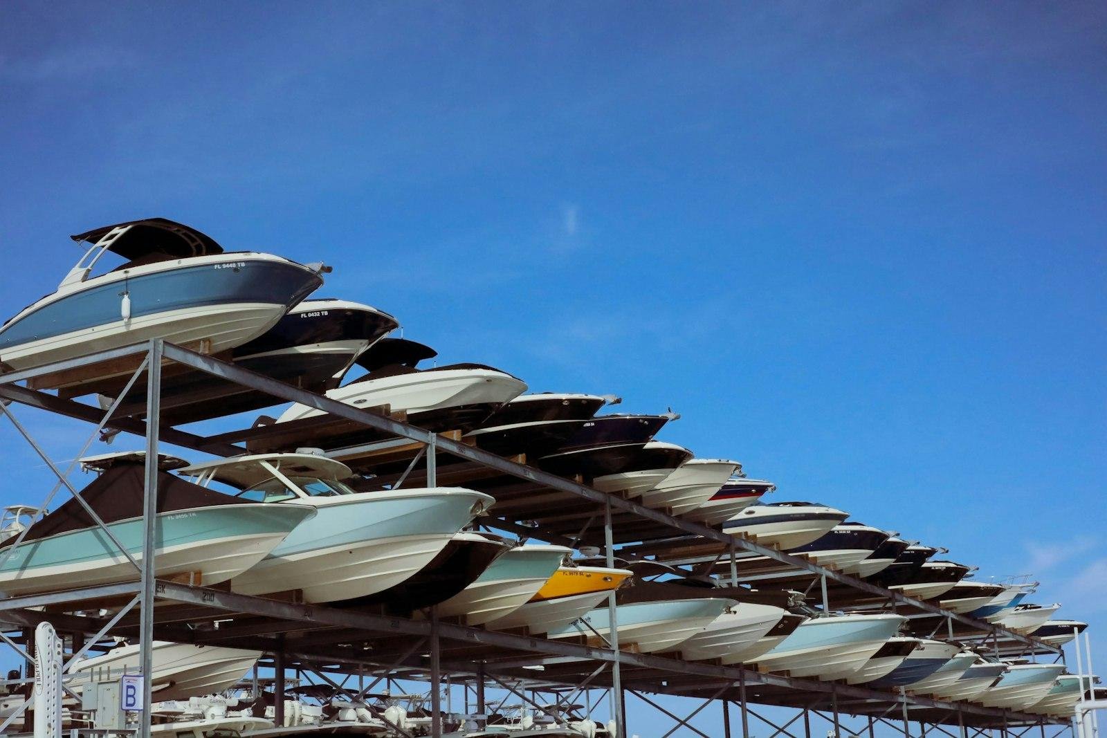 Rows of motorboats racked on a multi-level dry stack against a blue sky
