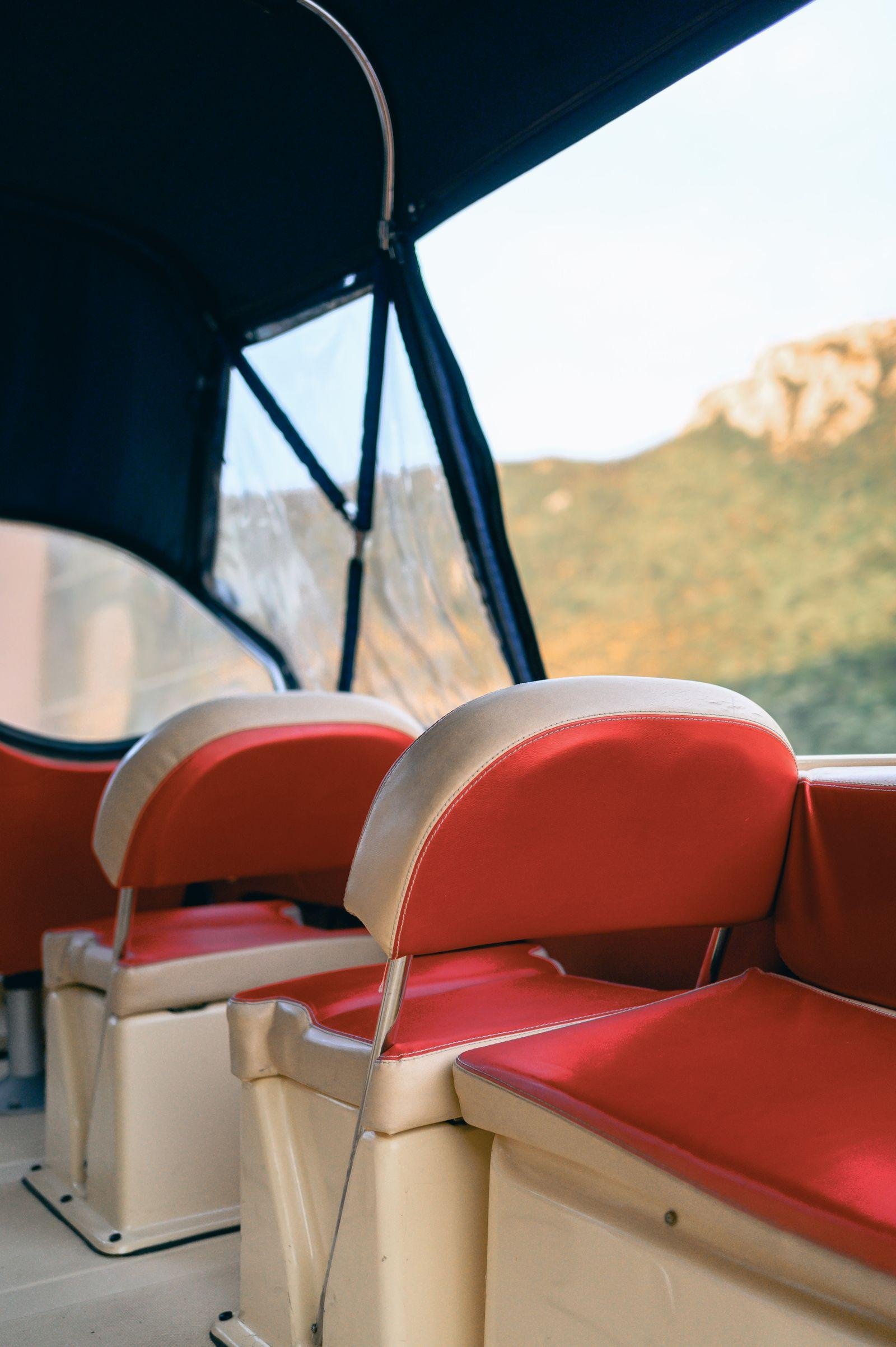 Red and cream vinyl boat seats and bench squabs under a canvas canopy on a sunny day