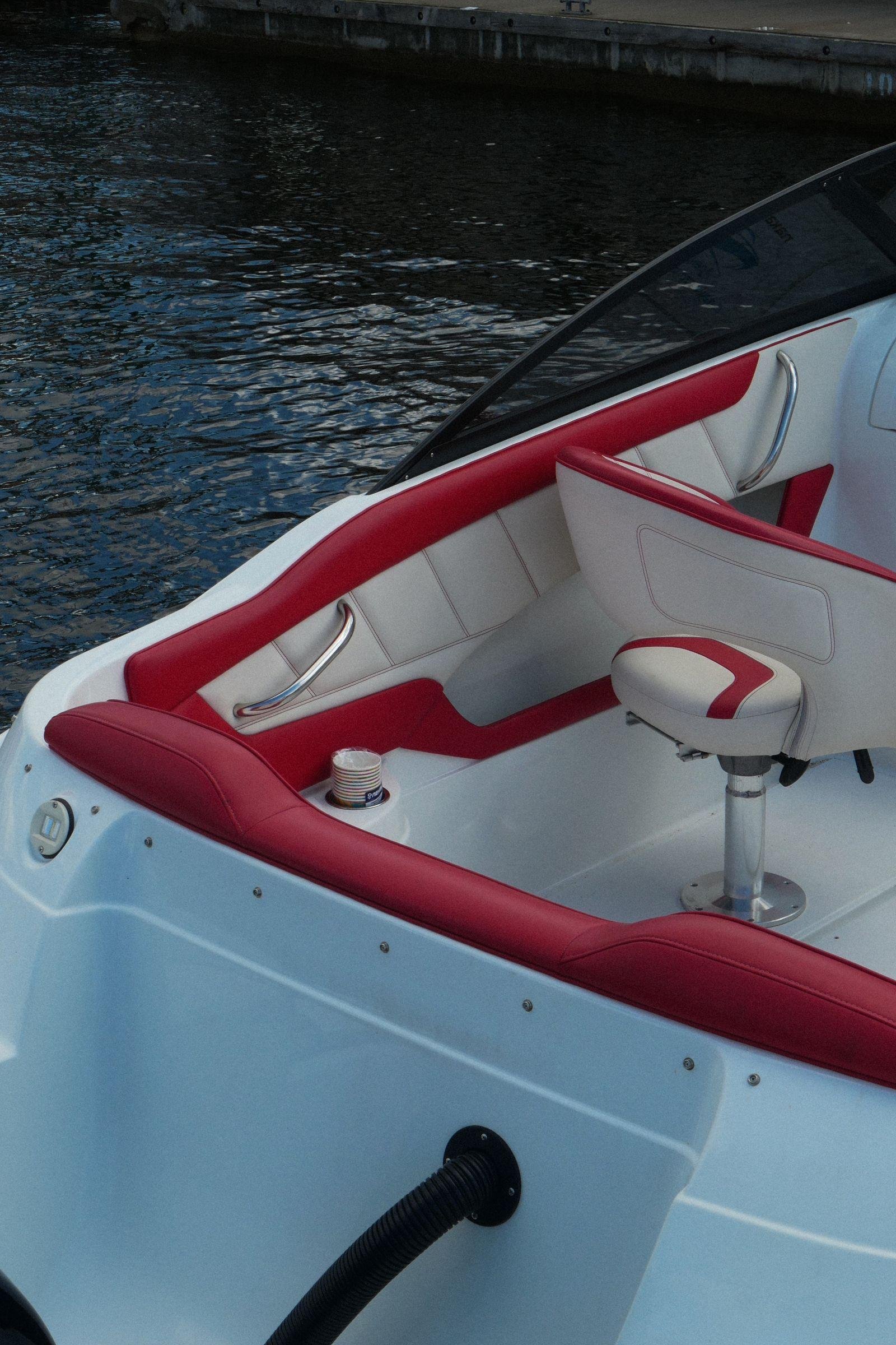 Red and white marine vinyl bow seating and helm seat on a runabout moored beside a wharf