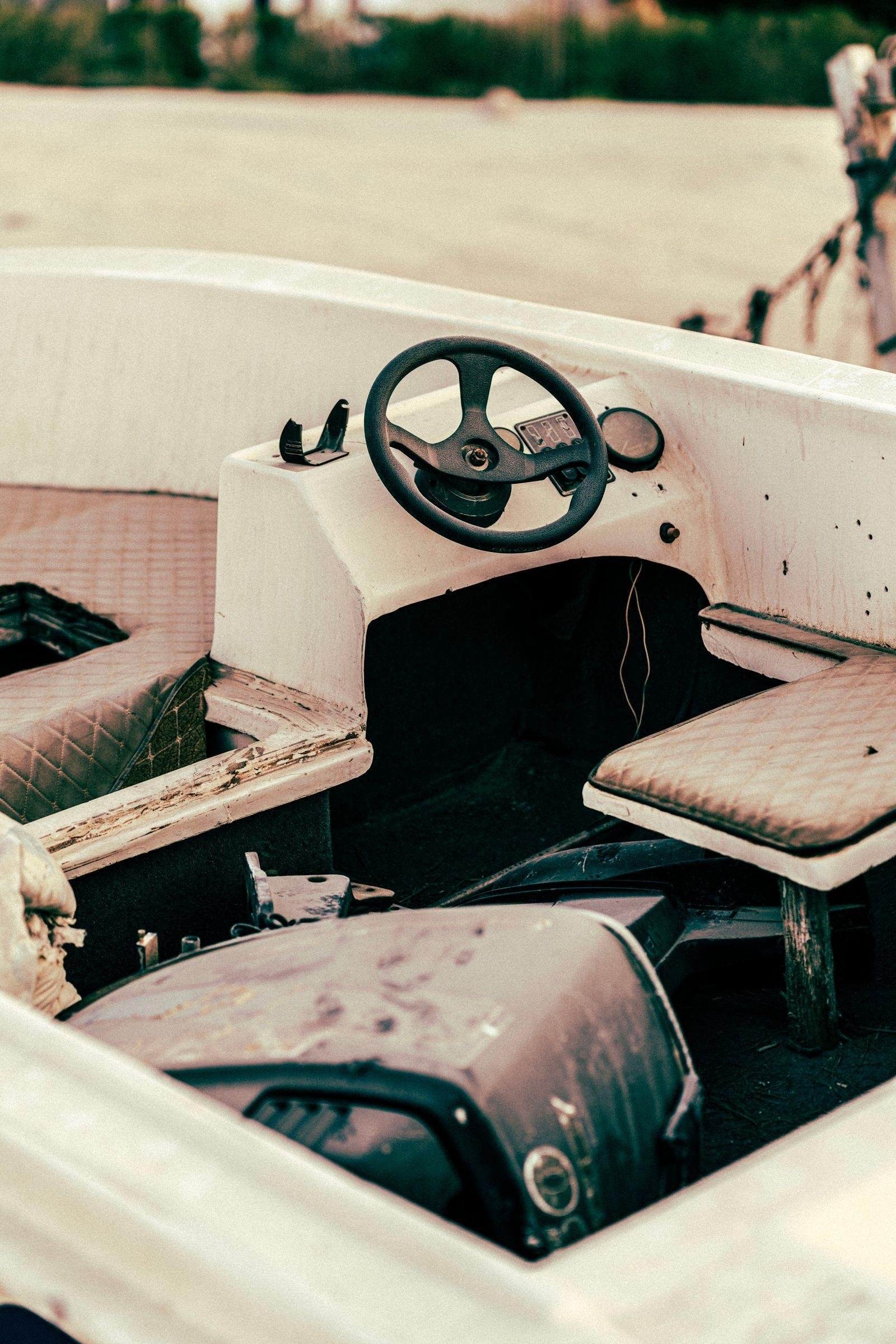 Faded, worn quilted vinyl seats and steering wheel inside an older white motorboat