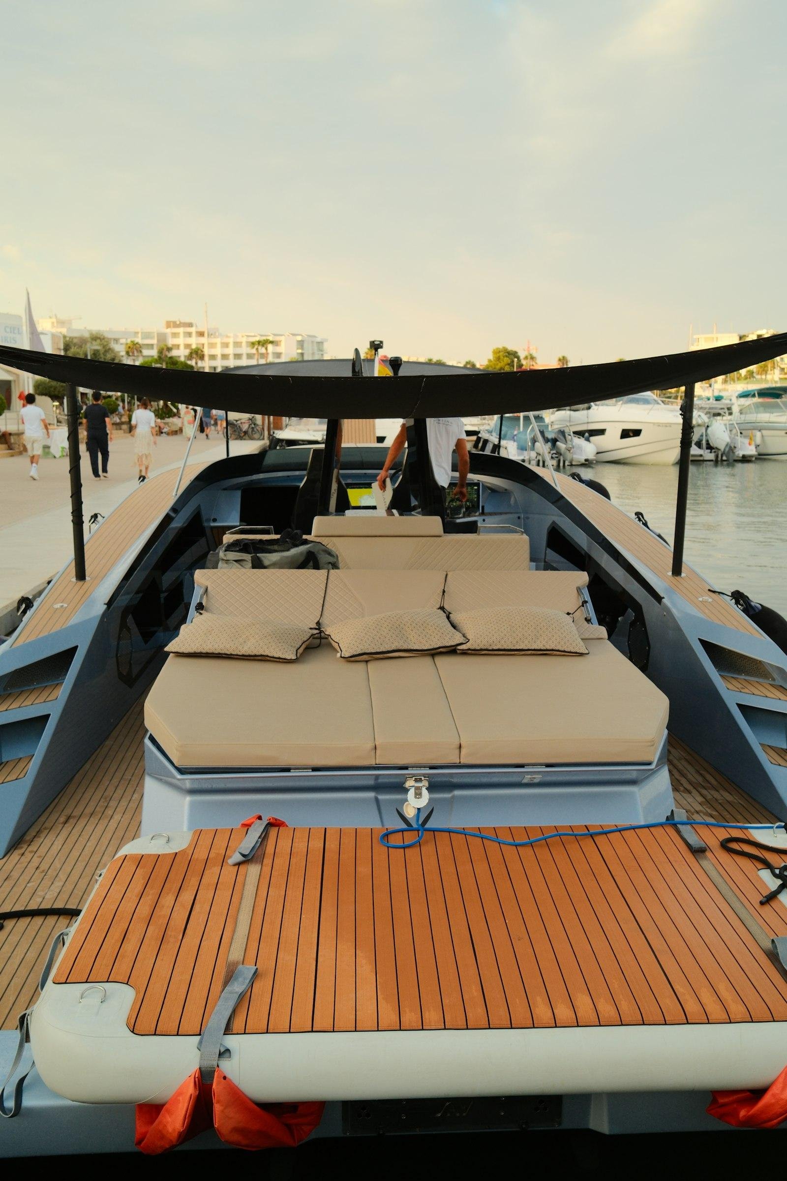 Tan upholstered sunpad cushions on the teak deck of a modern yacht berthed in a marina